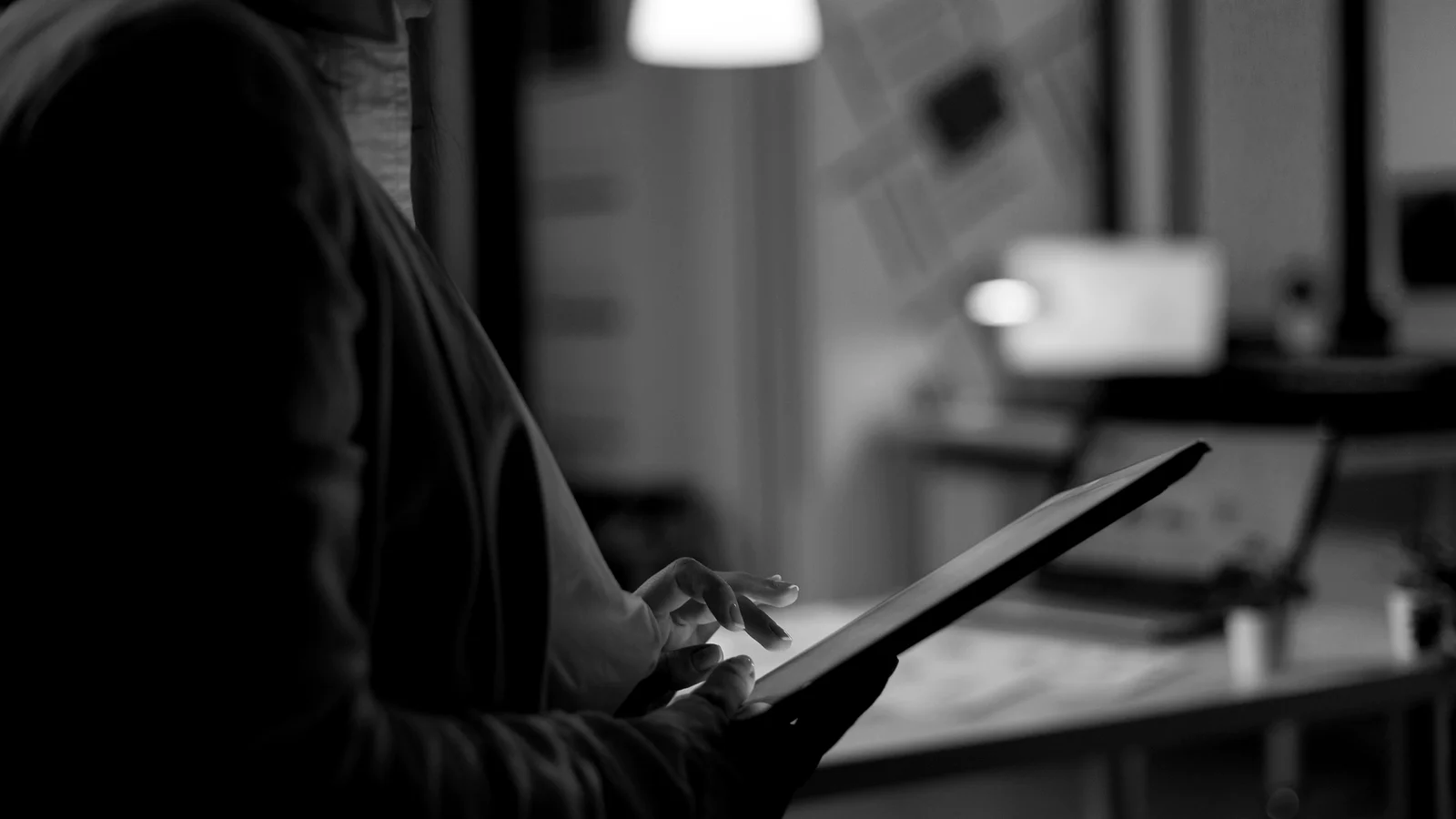 Close-up de mãos revisando dados em um tablet, luz baixa.